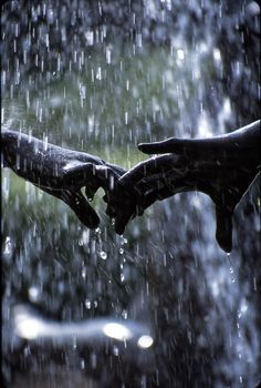 two hands holding each other in the rain