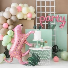 a party with balloons and decorations including a pink cat cake topper on a table