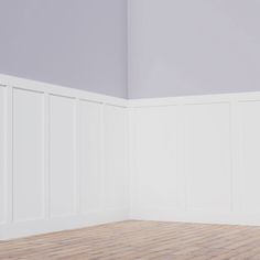 an empty room with white paneling on the walls and wood floor, in front of a gray painted wall