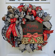 a christmas wreath with leopard print and red ribbon hanging on the front door to welcome guests