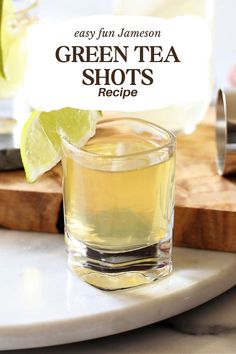 a glass filled with green tea sitting on top of a cutting board