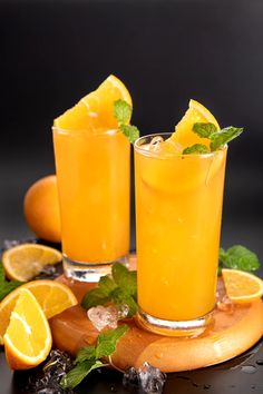 two glasses filled with orange juice and garnished with mint