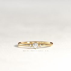 a yellow gold engagement ring with a single diamond in the center, sitting on a white surface