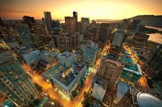 an aerial view of a city at night with the lights on and buildings lit up