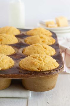 a muffin tin with twelve yellow cupcakes in it on a white table