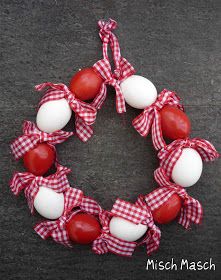 a red and white wreath made out of eggs on a black surface with the words mish masch written below it