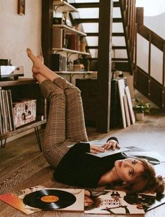 a woman laying on the floor with her feet up in front of a record player