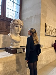 a woman standing next to a bust of a man