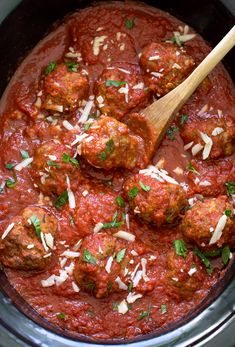 the meatballs are covered in marinara sauce and parmesan cheese with a wooden spoon