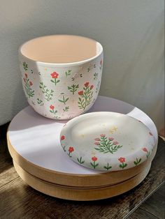 two bowls sitting on top of each other with flowers painted on the bottom and sides