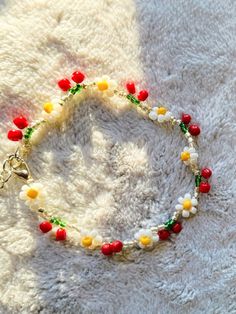 a bracelet with red, yellow and green beads on it sitting on a white blanket