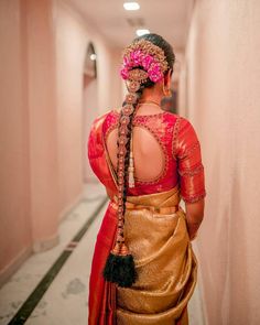 a woman in a red and gold sari is walking down the hallway with her back to the camera