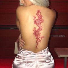 the back of a woman's body with a red dragon tattoo on her upper back