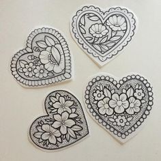 four heart shaped stickers with flowers and hearts drawn on the top one is black and white