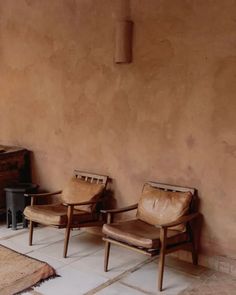 two chairs sitting next to each other in front of a wall