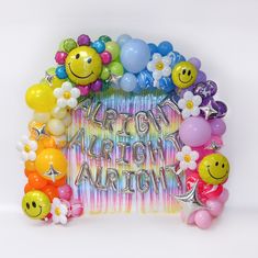 a bunch of balloons that are in the shape of a happy balloon arch with flowers and smiley faces