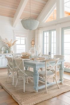 a dining room table with white chairs and an area rug on the floor in front of it