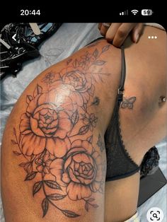 a woman's back with flowers on it and the side of her body covered in tattoos