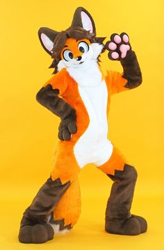 an orange and white fox mascot standing in front of a yellow background with one paw raised