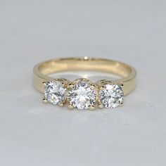 💙 14k solid gold three stone ring with premium grade D Color (colorless) moissanite gemstones. 💙 Unique design ring for engagement, wedding, anniversary and milestones. 💙 Our jewelry is handcrafted with love and great care at San Francisco Bay! 💙 You will receive them exactly as pictured. We don't use any filters, all photos are authentic and unedited. 💙 The ring material is 14k solid gold, should not be confused with gold plating or filling. It won't tarnish or fade over time. 💙 We're off Luxury White Moissanite Three Stone Wedding Ring, Luxury White Three-stone Moissanite Wedding Ring, Moissanite Three Stone Round Band For Wedding, Three Stone Moissanite Round Band For Wedding, Moissanite Three Stone Round Band Wedding Ring, Three Stone Moissanite Wedding Ring With Round Band, White Moissanite Three-stone Ring, White Three Stone Moissanite Rings, White Moissanite Three Stone Rings