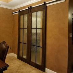 a dining room table with chairs and sliding glass doors on the wall behind it is a brown leather chair