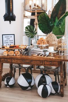 a table topped with lots of food and soccer balls next to a potted plant