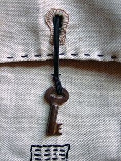 an old key is attached to the side of a white shirt with black stitching