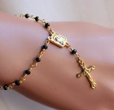 "This is a beautiful 18kt gold filled rosary style bracelet or anklet made with 3mm faceted black spinal stones and features a small crucifix cross pendant. This high quality ankle bracelet may be ordered in bracelet or anklet length, please choose size. Cross pendant measures 18x11mm, center Mary medallion measures 10x7mm. Spring clasp sits in back.If you prefer a plain cross you may request one at checkout. Comes nicely boxed for the perfect gift! May be ordered with other gemstone colors garn Black Rosary Bracelet As A Gift, Gold Rosary Bracelet With Black Beads As Gift, Elegant Black Rosary Bracelet For Gift, Cheap Black Spiritual Rosary Bracelet, Gold Hand-strung Rosary Bracelet As Gift, Black Hand-strung Rosary Bracelet As Gift, Black Rosary, 14kt Gold Jewelry, Gold Rosary