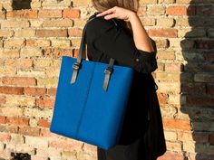 "A spacious carryall perfect for your daily life. This tote bag will carry you easily from the office to off-duty. The front stitching is completely handmade using a leather cord. The bag is soft and durable at the same time, because made of 100% merino wool felt. + 13.4x11.4x3\" - 34x29x8 cm + vegetable tanned leather straps - black + double-pocket inside + zip closure + a|M logo embossed by hand + color: bright blue 100% WOOL FELT is strong, lightweight and soft. It's 3 mm thick and has a high Blue Bags With Leather Trim And Double Handle, Blue Rectangular Shoulder Bag With Leather Trim, Blue Tote Bags With Leather Trim, Everyday Felt Tote Bag, Blue Shoulder Bag With Leather Trim For Daily Use, Rectangular Felt Bags For Daily Use, Blue Shoulder Bag With Leather Trim For Everyday, Rectangular Felt Travel Bag, Everyday Blue Shoulder Bag With Leather Trim