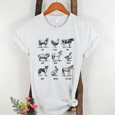 a t - shirt with different animals on it sitting next to a plant and flowers