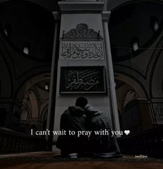 two men sitting on the ground in front of a clock tower with arabic writing written on it