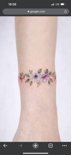 a woman's foot with a flower tattoo on her left ankle and pink flowers on the side