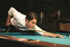 a woman leaning over a pool table with a cue in her hand