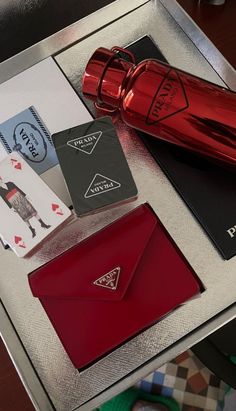 a red bottle and some cards on a table with other items around it, including a card case