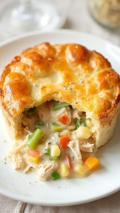 a chicken pot pie on a white plate with a bite taken out of it's crust