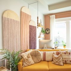 a living room filled with lots of furniture next to a window and potted plants