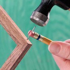 a person holding a pencil and an object in their hand that looks like a hammer