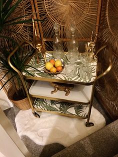 a table topped with two trays filled with fruit next to a potted plant