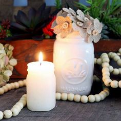 a white candle sitting on top of a wooden table next to a beaded necklace