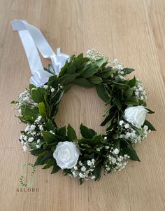 a wreath with white roses and baby's breath on a wooden table, ready to be used as a wedding decoration