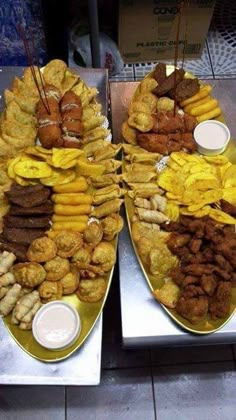 two trays filled with different types of food on top of metal trays next to each other