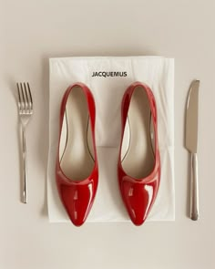 a pair of red high heels sitting on top of a napkin next to a fork and knife