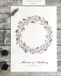 an image of a wedding card with flowers and leaves in the middle on a wooden table