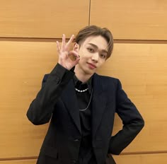 a woman wearing a black suit and necklace posing for the camera