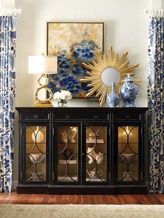 a blue and white vase sitting on top of a wooden cabinet next to a window