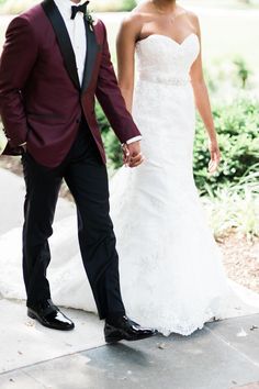 the bride and groom are holding hands as they walk down the sidewalk together in their wedding attire