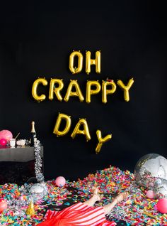 a woman laying on top of a pile of confetti next to a sign that says oh crappy day