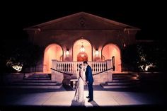 a bride and groom standing in front of a building at night