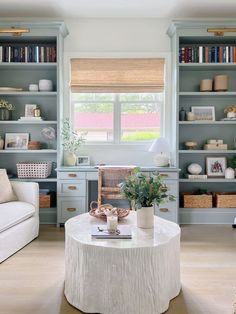 a living room filled with furniture and bookshelves next to a window covered in blinds