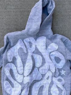 a blue and white hoodie with the word boo on it's chest, sitting on a gray surface